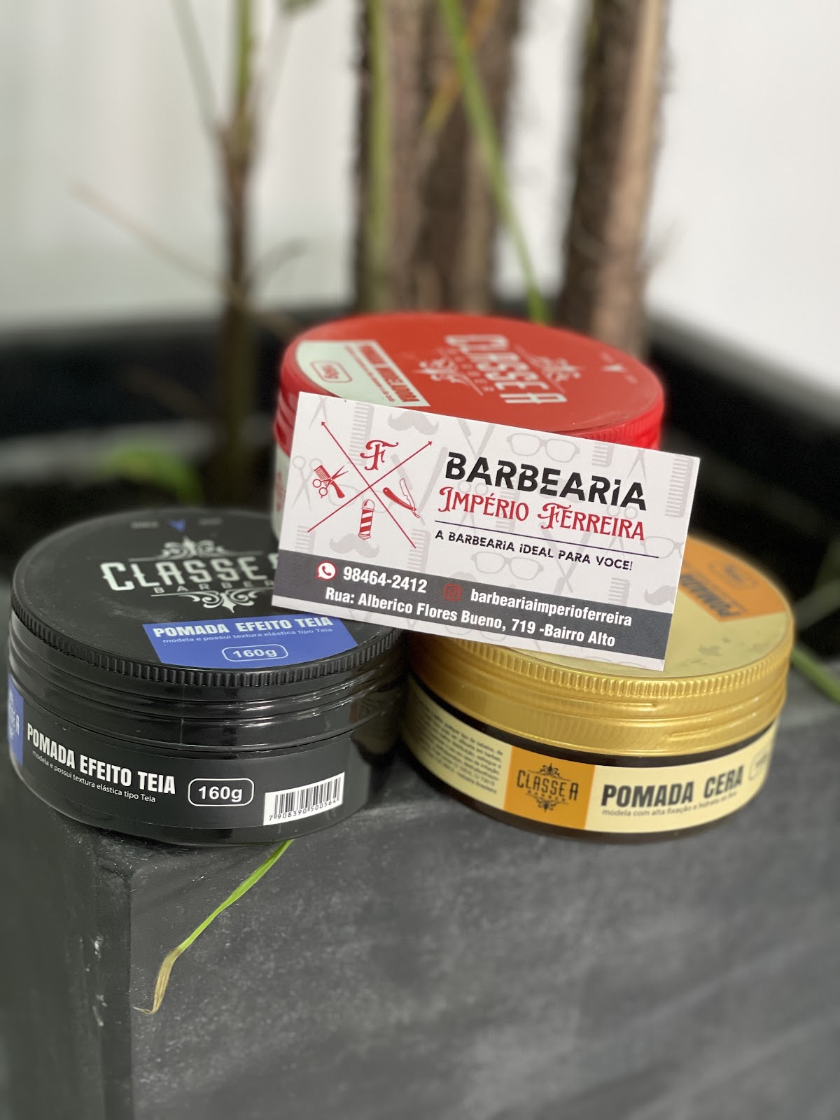 Cartão e pomadas de cabelo com a identidade da Barbearia Império Ferreira